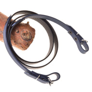 Die Hobby Horse LarDen Zügel gummiert anthrazit sind dunkle gebisslose Zügel für Zaumzeug mit Metallschnallen und einer strukturierten Innenseite, über Holz gelegt und vor weißem Hintergrund gezeigt.