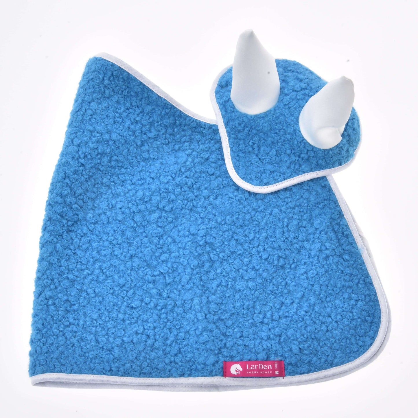 Set Mystery von Hobby Horse LarDen mit blauem strukturiertem Babylätzchen und passender Mütze mit weißen Hörnern und weißem Besatz, die an ein verspieltes Pferd erinnern. Ein rosa Etikett setzt einen Akzent auf dem Lätzchen und macht dieses Set zu einem niedlichen, von Fliegenhauben inspirierten Accessoire für kleine Kinder.