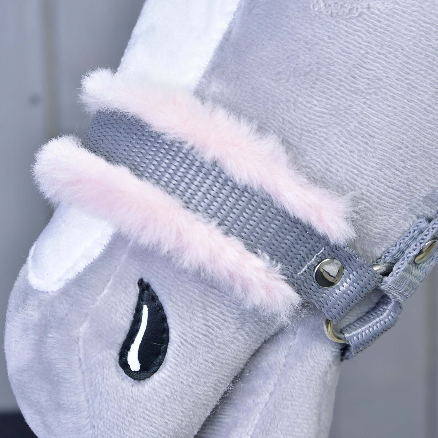 Gros plan sur le Licol gris avec fourrure rose de Hobby Horse LarDen, avec tissu gris en peluche, tache blanche, bordure en fausse fourrure rose, détail noir brodé en forme de goutte et rivets métalliques, parfait pour votre animal en peluche ou votre Hobby Horse.