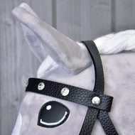 Close-up of a gray plush horse’s head wearing the Hobby Horse LarDen Complete black bridle with diamonds. The horse has a white mane, upright ear, cartoon-style eye, and light wood planks form the background.