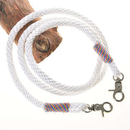 Rênes blanches de Hobby Horse LarDen avec mousquetons métalliques aux deux extrémités et fil multicolore près de chaque mousqueton, enroulées sur du bois sur fond blanc, évoquant l’apparence de rênes de bride sans mors de haute qualité.