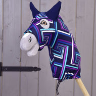 Hobby Horse LarDen Hobby Horse Schutzanzug blau (Lycra) zeigt einen Kopf mit farbenfrohem geometrischem Muster, großem braunem Auge, schwarzen Ohren und weißer Schnauze auf einem Holzstab, vor einem Holzzaun.