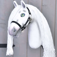 Hobby Horse Quicksilver mit Schwarzem Halfter von Hobby Horse LarDen mit langer Garnmähne, grünen Augen und grauer Schnauze vor rustikalem Holzhintergrund.