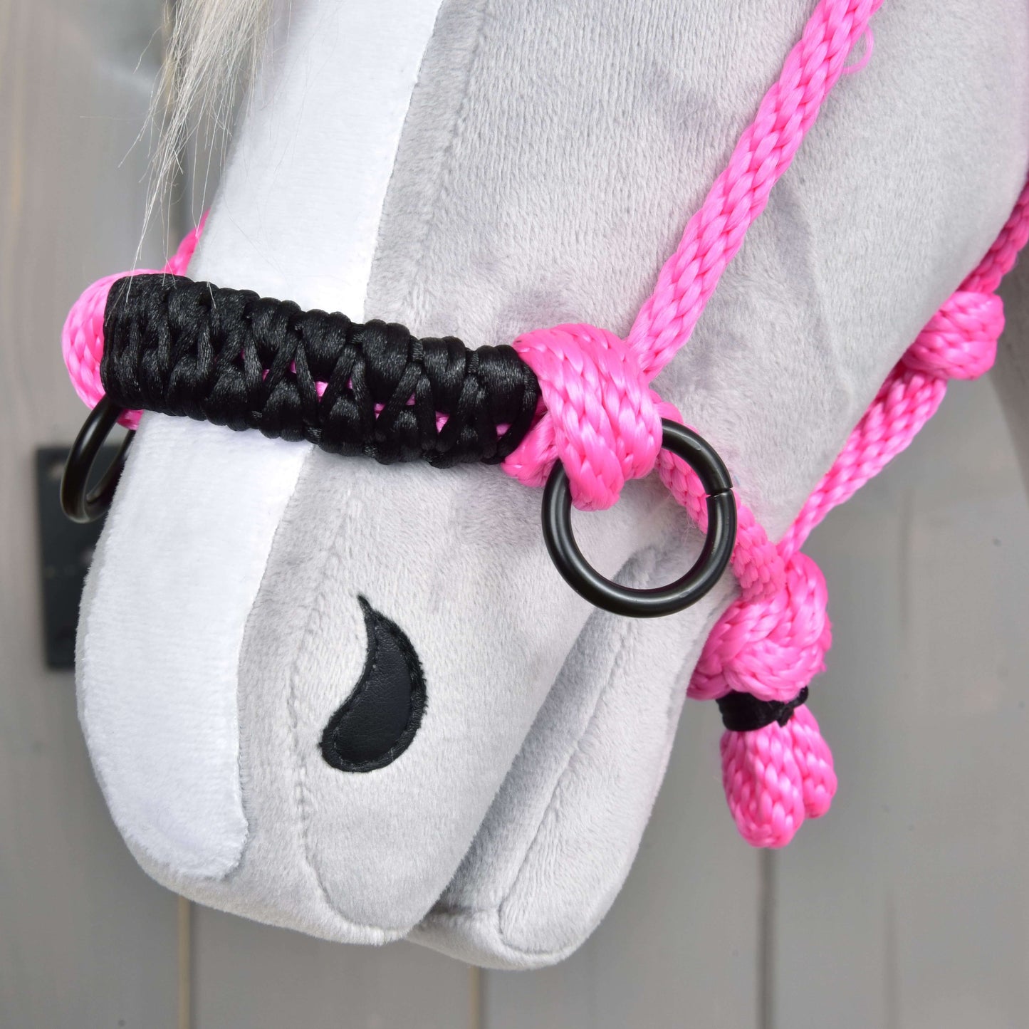 Close-up of a gray plush horse’s face wearing the Rope halter Pink by Hobby Horse LarDen, featuring vibrant pink rope with black and pink knots, metal rings, and a black stitched nostril.