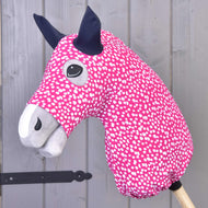 Hobby Horse LarDen "Hobby Horse Schutzanzug Minie (Lycra)" als pinkes Hobby Horse mit weißen Flecken, grauer Schnauze, schwarzen Ohren und Holzstabgriff; mit waschbarem Lycra-Bezug für einfache Reinigung.