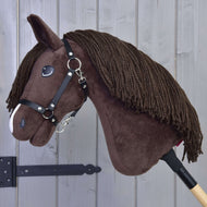 Hobby Horse LarDen Hobby Horse Chianti mit Schwarzem Halfter mit braunem Körper, Garnmähne und weißem Nasendetail, auf einem Holzstab vor einer hellgrauen Holzwand.