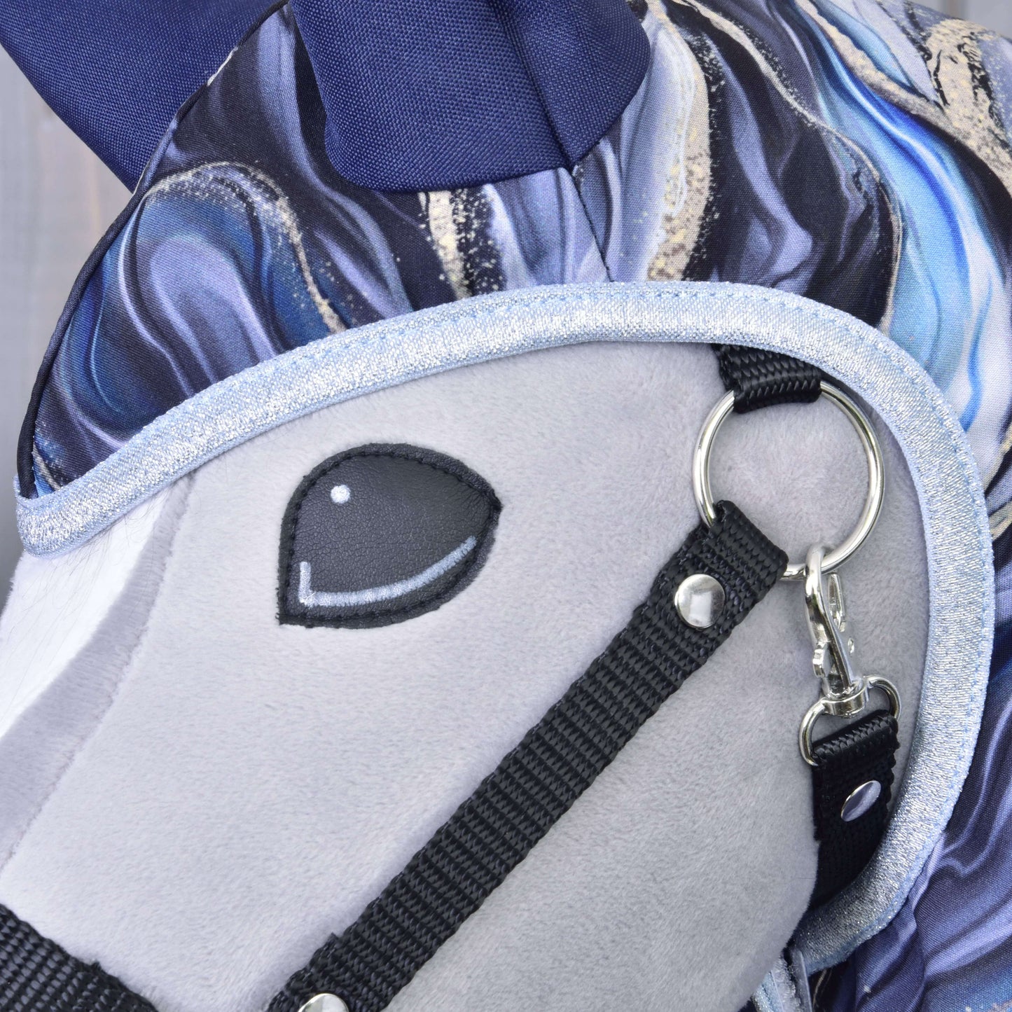 Nahaufnahme des Plüschkopfes von Hobby Horse LarDen Regendecke Galaxy Cobalt mit weichem grauem Gesicht, gesticktem schwarzem Auge, glänzendem silbernem Besatz am Zaumzeug und blau-weiß gemusterter Mähne – ideal als Ergänzung zu deinen liebsten Hobby Horse Accessoires.