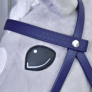 Close-up of a plush horse’s face with a stitched black and white eye, wearing the Hobby Horse LarDen Complete bridle with noseband in Dark Purple; the bridle features a silver button detail and the horse’s fur is light gray.