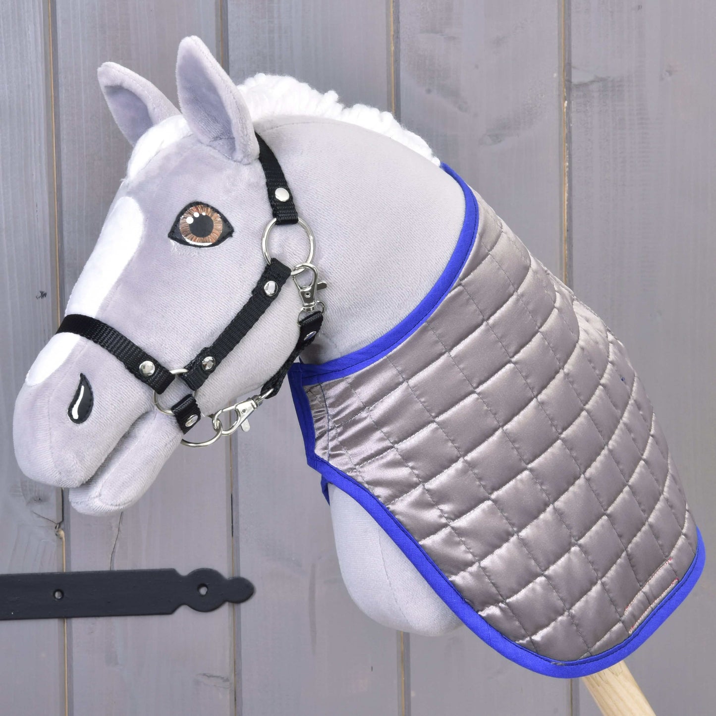 Decke DeLuxe Blue doppelseitig von Hobby Horse LarDen an einem grauen Plüsch-Hobby Horse mit schwarzem Zaumzeug vor einem grauen Holzhintergrund.