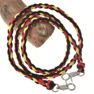 Hobby Horse LarDen Zügel Flag ist ein geflochtener Führstrick aus Polypropylenseil in Schwarz, Rot und Gelb, um Holz gewickelt und inspiriert von handgefertigten Zügeln. Er verfügt an beiden Enden über silberne Metallverschlüsse.