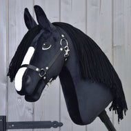 Hobby Horse Freya mit Schwarzem Halfter von Hobby Horse LarDen mit schwarzem Stoff, weißer Blesse und langer schwarzer Garnmähne, inspiriert vom Irish Cob, vor hellem Holz-Hintergrund.