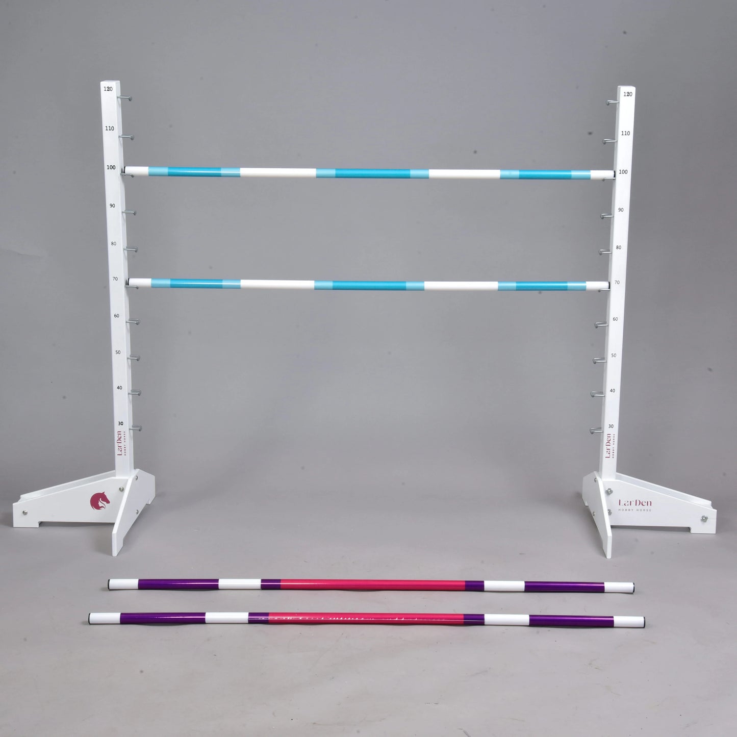 Obstacle 120 cm / 47 inch avec poteaux supplémentaires de Hobby Horse LarDen, avec support réglable blanc tenant deux barres rayées bleues et blanches, plus des poteaux rouges et violets sur un sol gris. Parfait pour le Hobby Horsing, sur fond gris uni.