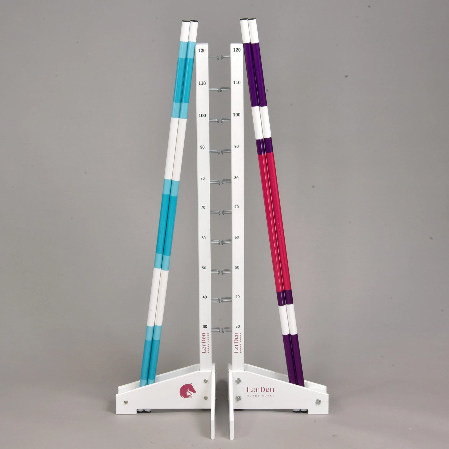 Obstacle 120 cm / 47 inch avec poteaux supplémentaires de Hobby Horse LarDen, avec deux supports blancs à marquages de mesure tenant trois poteaux rayés — deux bleus et un violet. Cet obstacle réglable convient à l'entraînement de Hobby Horsing en intérieur ou en extérieur, sur fond gris.