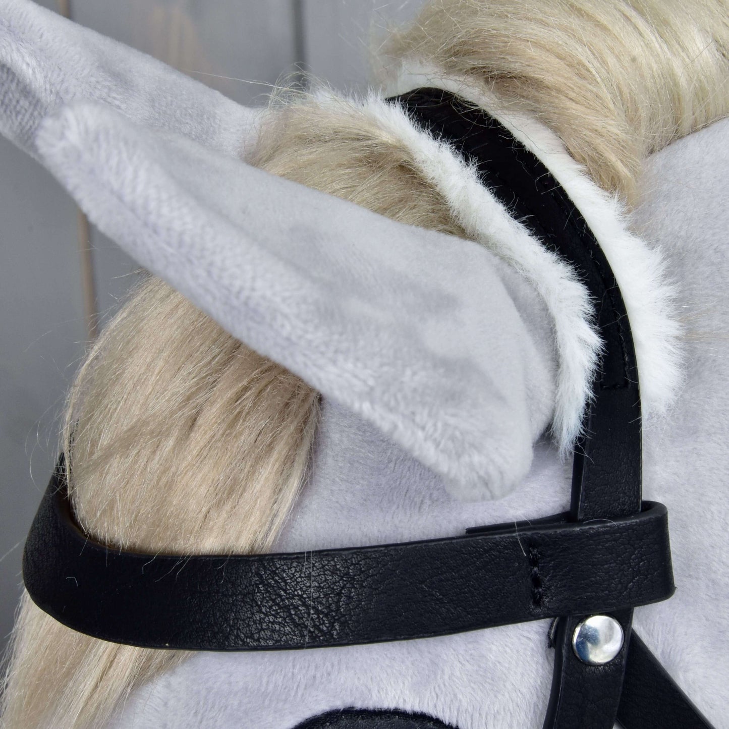 Nahaufnahme eines hellgrauen Plüschpferdekopfs mit Hobby Horse LarDen Komplette Trense mit Fell, mit Fokus auf Ohr, Trense und die flauschigen Details der blonden Mähne dieses realistischen Hobby Horse.