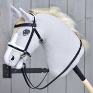 Hobby Horse LarDen Komplette Trense mit Fell an einem hellgrauen Hobby Horse mit cremefarbener Mähne, schwarzer Trense aus Kunstleder und Zügeln auf einem Holzstab, vor grauem Holzhintergrund.