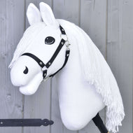 Das Hobby Horse LarDen „Hobby Horse Lady mit Schwarzem Halfter“ zeigt ein weißes Pferd mit schwarzem Halfter und langer Garnmähne auf einem Stock, posiert wie bereit für Dressur vor einer hellgrauen Holzwand.