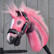 Hobby Horse LarDen Pinkie mit glitzerdem Halfter, limitierte Edition, mit flauschiger Mähne und weißer Zeichnung im Gesicht, vor grauen Holzpaneelen.