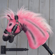 Hobby Horse LarDen Pinkie mit glitzerdem Halfter von Hobby Horse LarDen, limitierte Edition, auf einem Stab montiert und vor einer grauen Holzwand positioniert.