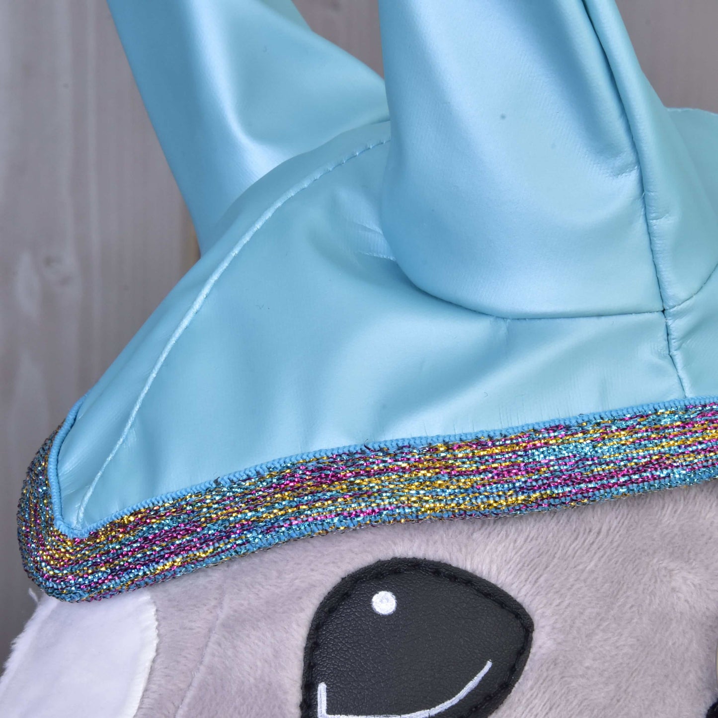 Nahaufnahme der Regendecke Light Blue von Hobby Horse LarDen mit glänzenden blauen Details, glitzernder mehrfarbiger Einfassung und weichem grauem Stoff – perfekt für deine Hobby Horse Abenteuer bei jedem Wetter.