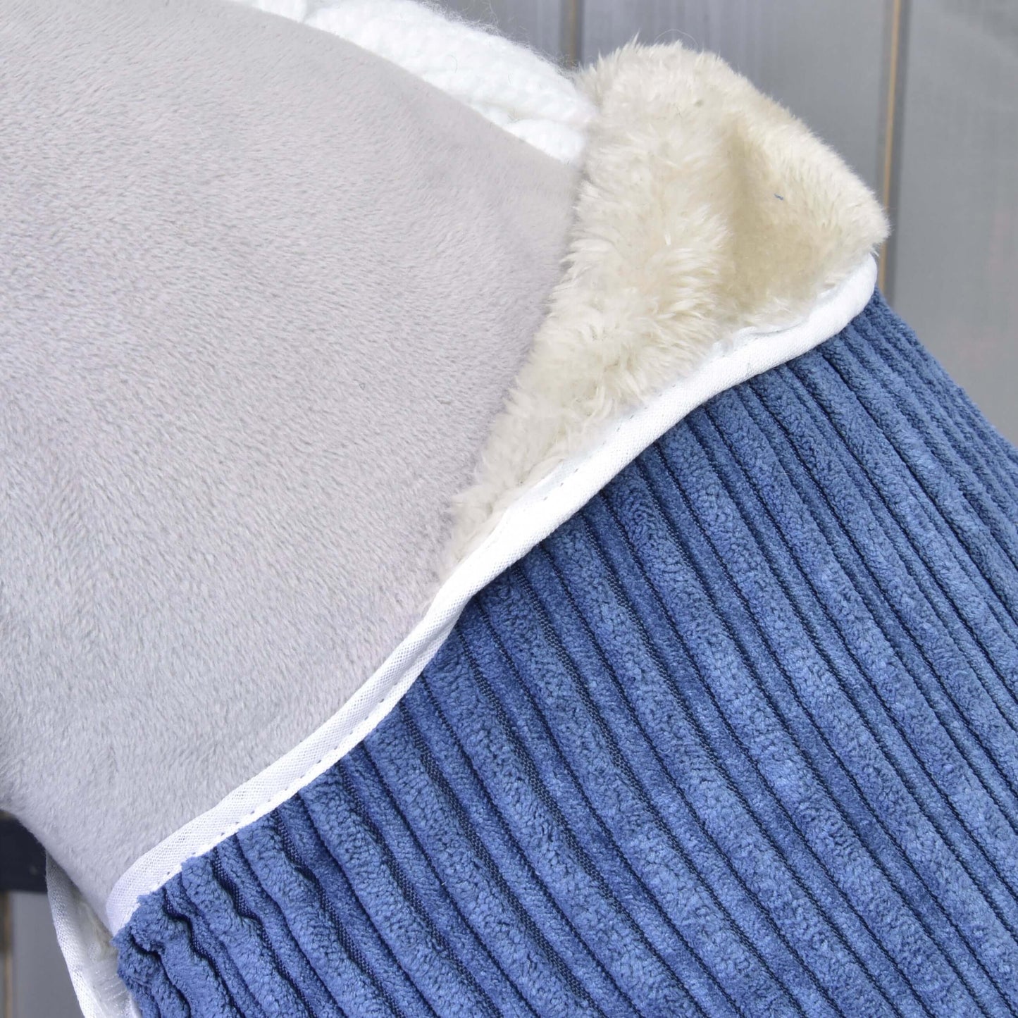 Nahaufnahme des Deckensets Set Manchester Plum von Hobby Horse LarDen mit drei Bereichen – hellgrauem Fleece, cremefarbenem Sherpa und blauem geripptem Stoff – jeweils mit weißer Einfassung.