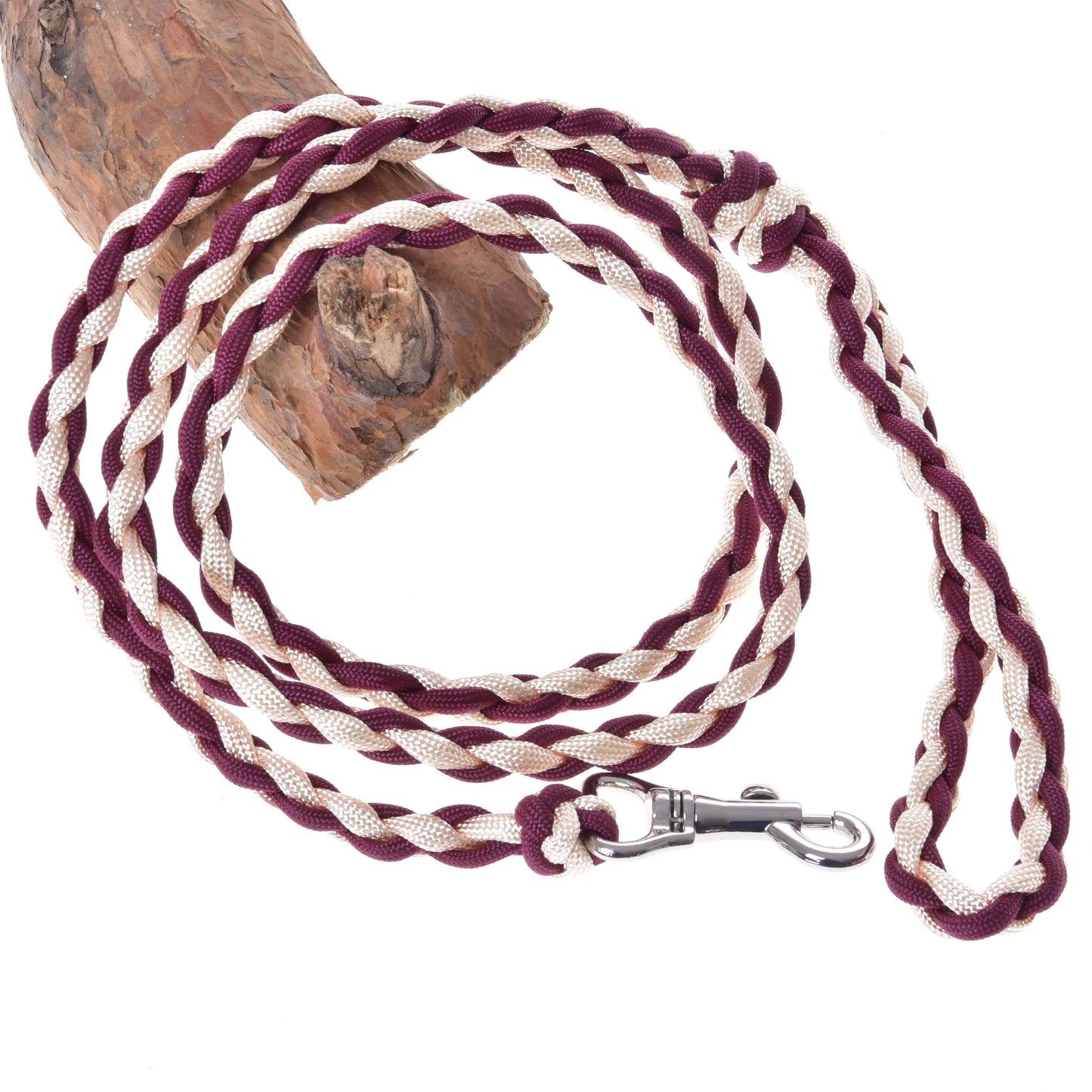 Hobby Horse - Führstrick Knitted Maroon von Hobby Horse LarDen mit geflochtener kastanienroter und weißer Paracord sowie einem Metallverschluss, aufgewickelt neben einem Ast.