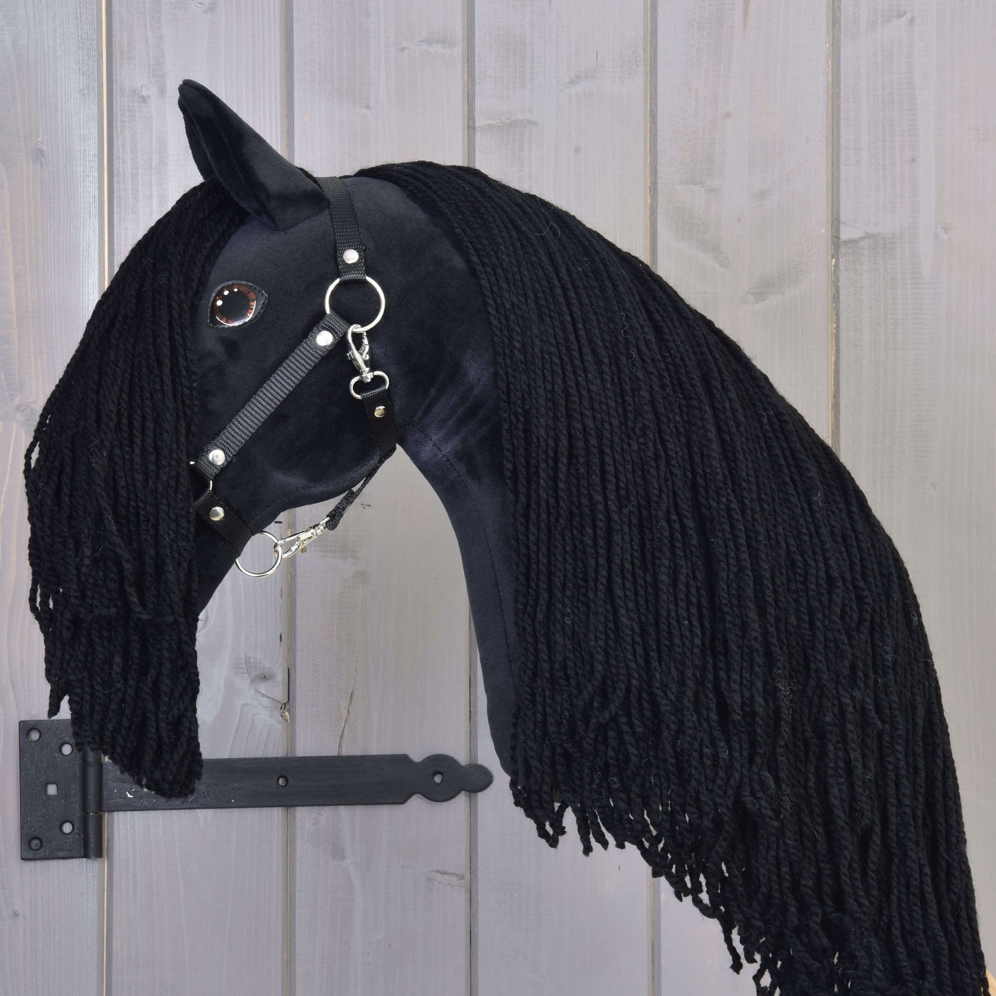 Hobby Horse Maximus avec licol noir de Hobby Horse LarDen, jouet étalon noir fait main avec longue crinière en fil, bride noire brillante et œil en bouton, monté sur bois avec support métallique noir.