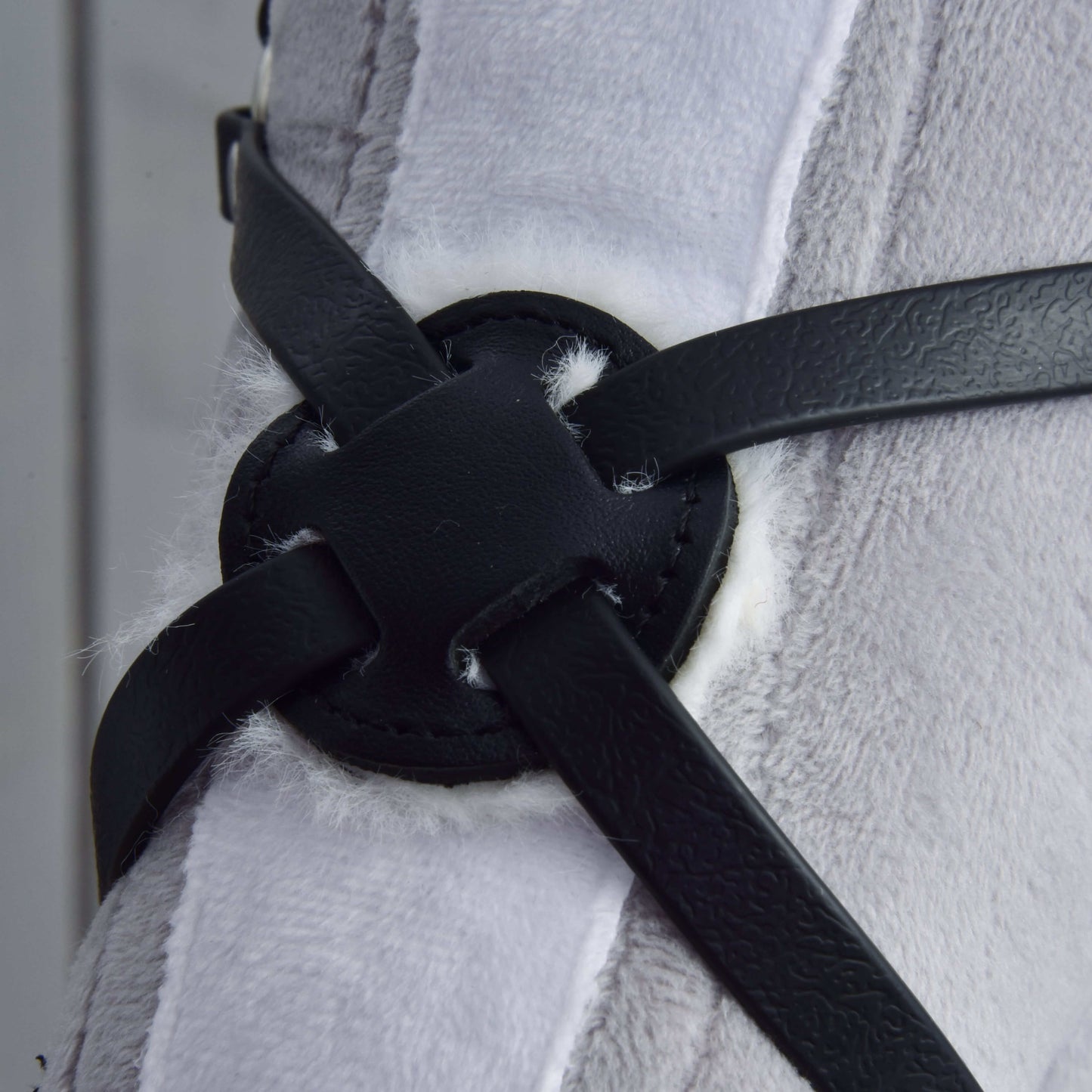 Nahaufnahme des Reithalfter Mexico schwarz gepolstert von Hobby Horse LarDen mit schwarzen Riemen aus Kunstleder über einem runden Aufnäher auf plüschigem weißem und grauem Stoff – perfekt in Detail und Komfort für jeden Hobby Horse Fan.
