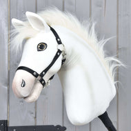 Hobby Horse Nexus mit Schwarzem Halfter von Hobby Horse LarDen mit einem weißen Plüschkopf im von Akhal-Teke inspirierten Stil mit Knopfauge und flauschiger Mähne, vor einer Holzwand präsentiert – ideal für jeden Hobby Horse Nexus Fan.