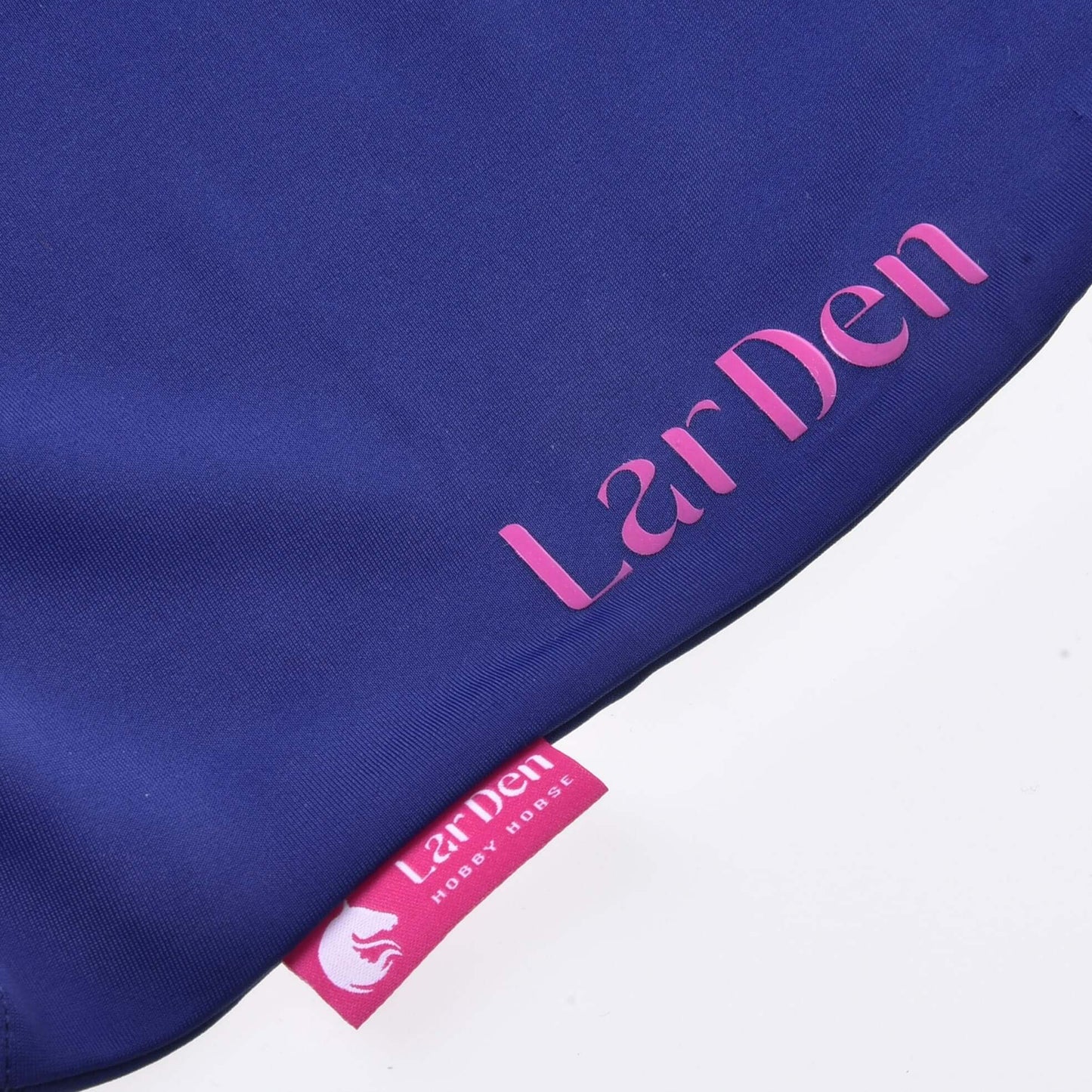 Gros plan sur du lycra bleu avec « Hobby Horse LarDen » en rose et une étiquette rose avec logo cheval, idéal pour les fans de Hobby Horse à la recherche d'une Combinaison de protection Hobby Horse LarDen élégante.