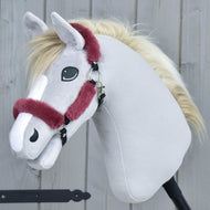 Das Hobby Horse LarDen Fellhalfter Teddy Maroon mit hellgrauem Fell, cremefarbener Mähne und bordeauxfarbenem Halfter ist aufrecht vor einem Hintergrund aus Holzwand dargestellt.