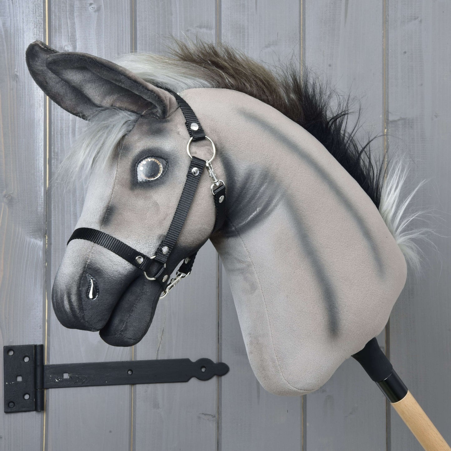 Hobby Horse LarDen Esel Olin mit Schwarzem Halfter mit grauem Plüschkörper, flauschiger Mähne, schwarzem Halfter für Hobby Horse und montiert auf einem Holzstab, perfekt zum Spielen oder Ausstellen vor jedem Hintergrund.