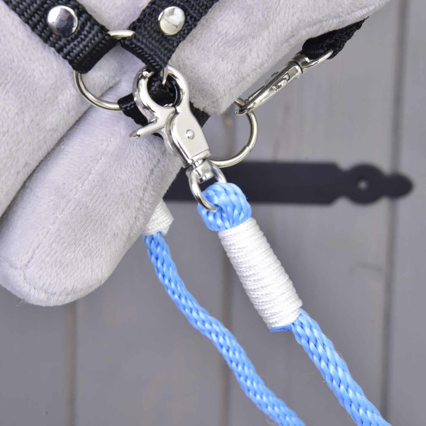 Close-up of Hobby Horse LarDen's Reins Sky—a blue polypropylene rope leash with a metal clasp on a black hook, set against light grey soft material in the background.