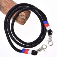 Hobby Horse LarDen Zügel Emblem CZ ist eine schwarze geflochtene Kordel aus Polypropylen mit Metallkarabinern und roten, blauen und weißen Fadenakzenten nahe den Karabinern, auf Holz aufgewickelt vor weißem Hintergrund.