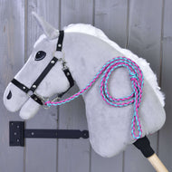The Hobby Horse LarDen Hobby Horse - Knitted Lead Rope Pinkie-Blue, with a plush gray body, black bridle, white mane, and braided pink and teal lead rope, hangs on a wooden wall. Stick handle included.