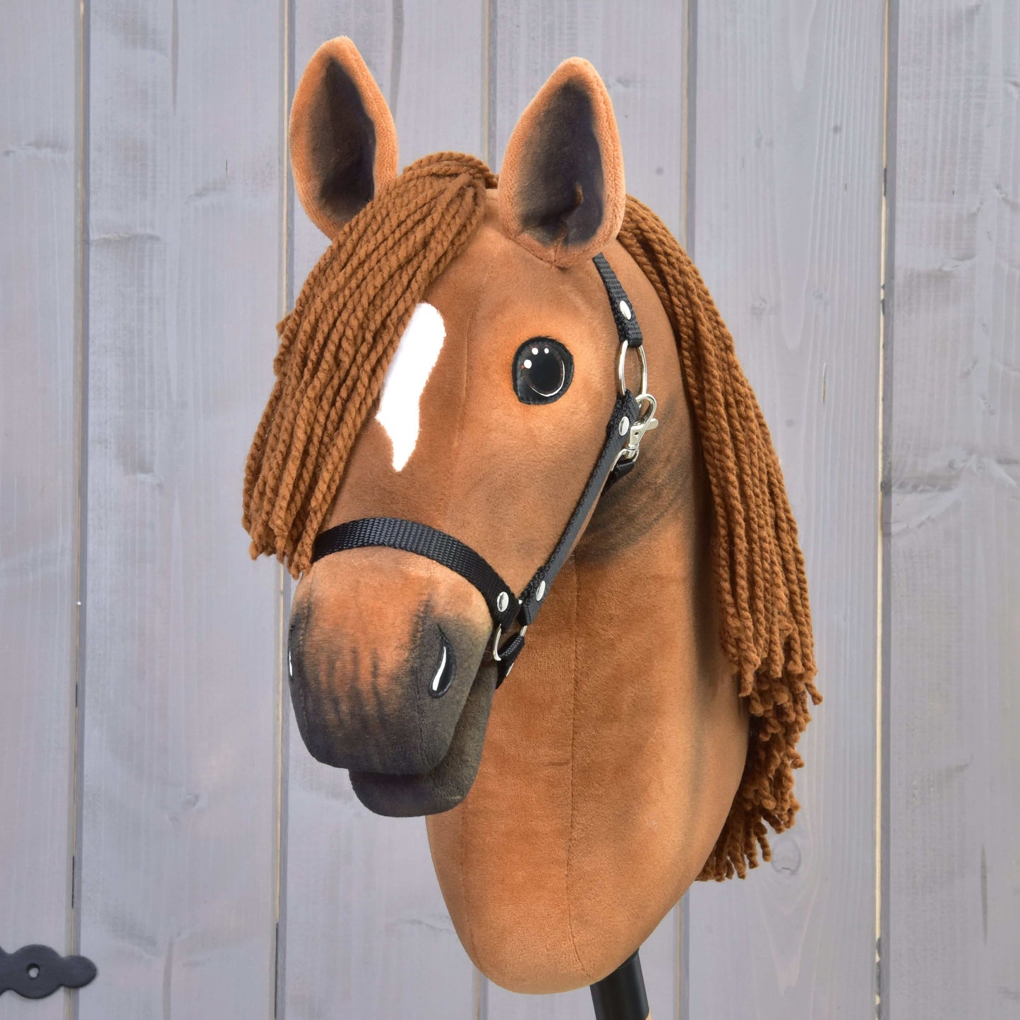 Hobby Horse Pippa avec licol noir de Hobby Horse LarDen avec design de jument alezane, crinière brune en fil, licol noir et marque blanche sur le front, présenté sur fond en bois clair.