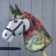 Regendecke Galaxy von Hobby Horse LarDen zeigt ein realistisches graues Hobby Horse mit schwarzem Zaumzeug und einer marmorierten Allwetter-Kopf- und Halsabdeckung im Regenmantel-Stil in Grün, Rot und Creme vor Holz-Hintergrund.