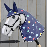 Die Hobby Horse LarDen "Regendecke Rainy" ist ein plüschiges Hobby Horse mit Pferdekopf auf einem Holzstab, das eine blaue Allwetter-Regenhaube mit buntem Schirmmuster und dunkelblauen Ohren trägt, gezeigt vor einer grauen Holzwand.