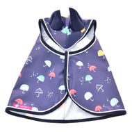 Die Regendecke Rainy von Hobby Horse LarDen ist ein dunkelblauer Allwetter-Hunderegenmantel mit bunten Schirm- und Regentropfenmustern, Frontreißverschluss und umgelegtem Kragen – ideal als Regenmantel für Spaziergänge an regnerischen Tagen oder für Hobby Horse Abenteuer.