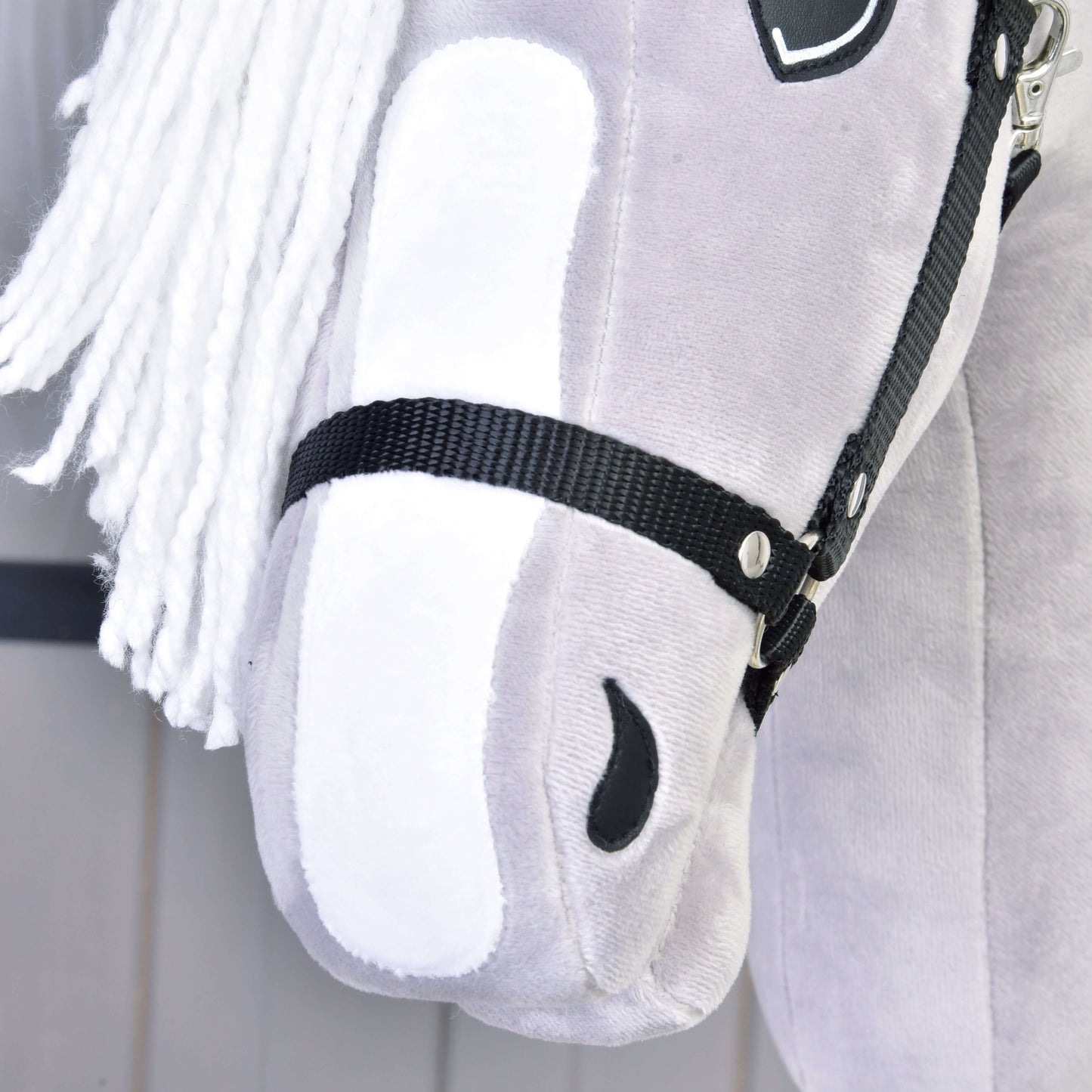 Nahaufnahme von Hobby Horse LarDen's grauem Plüsch-Hobby Horse Popcorn mit Schwarzem Halfter, inspiriert von einem Englischen Vollblut, mit weißer Garnmähne, schwarzem Halfter und weichen gestickten Details, einschließlich eines schwarzen Nüsterns.