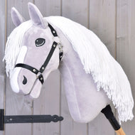 Hobby Horse LarDen Hobby Horse Popcorn mit Schwarzem Halfter mit hellgrauem Kopf, weißer Garnmähne, schwarzem Halfter und Holzstabgriff. Ideal als fantasievolles Spiel und Familien-Pferdeabenteuer. Vor einer Holzwand präsentiert.