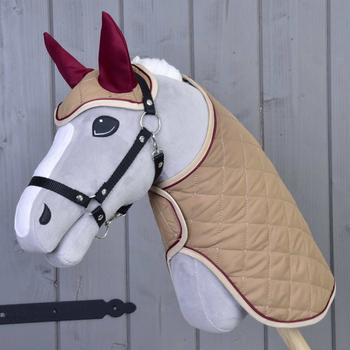 Set Roma von Hobby Horse LarDen ist ein plüschiges Hobby Horse mit hellgrauem Gesicht, schwarzem Zaumzeug, hellbraunem gestepptem Mantel und bordeauxfarbener Fliegenhaube – ideal für fantasievolles Spielen oder zum Kombinieren mit einem Deckenset.