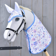 The Hobby Horse LarDen Set Vanessa NEW features a gray hobby horse with a black bridle, blue-trimmed floral blanket set, and matching ear bonnet, all displayed against a wooden background.