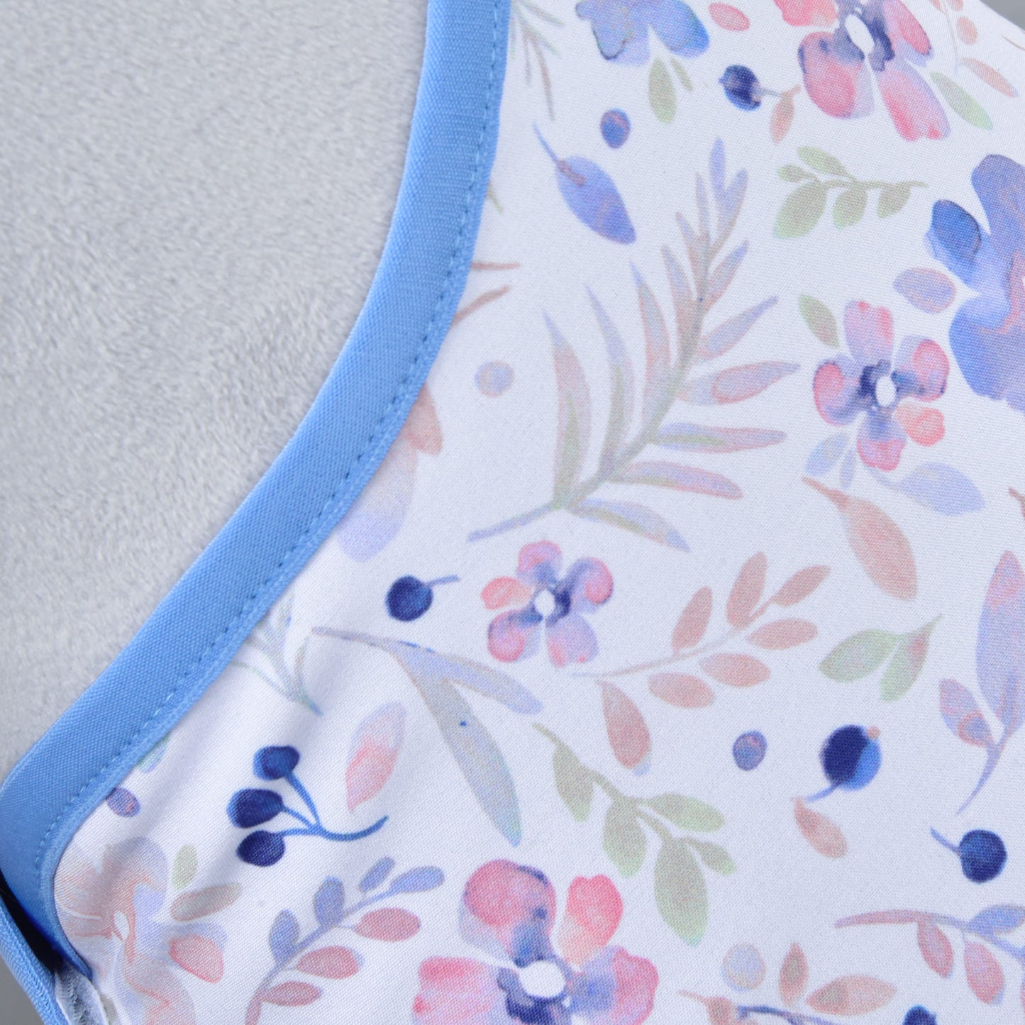 Gros plan du Set Vanessa NEW de Hobby Horse LarDen, en tissu Winter Softshell avec bordure bleue et motif floral pastel — fleurs roses, violettes et bleues avec feuilles vertes — idéal comme ensemble couverture et bonnet d'oreilles douillet pour Hobby Horse.