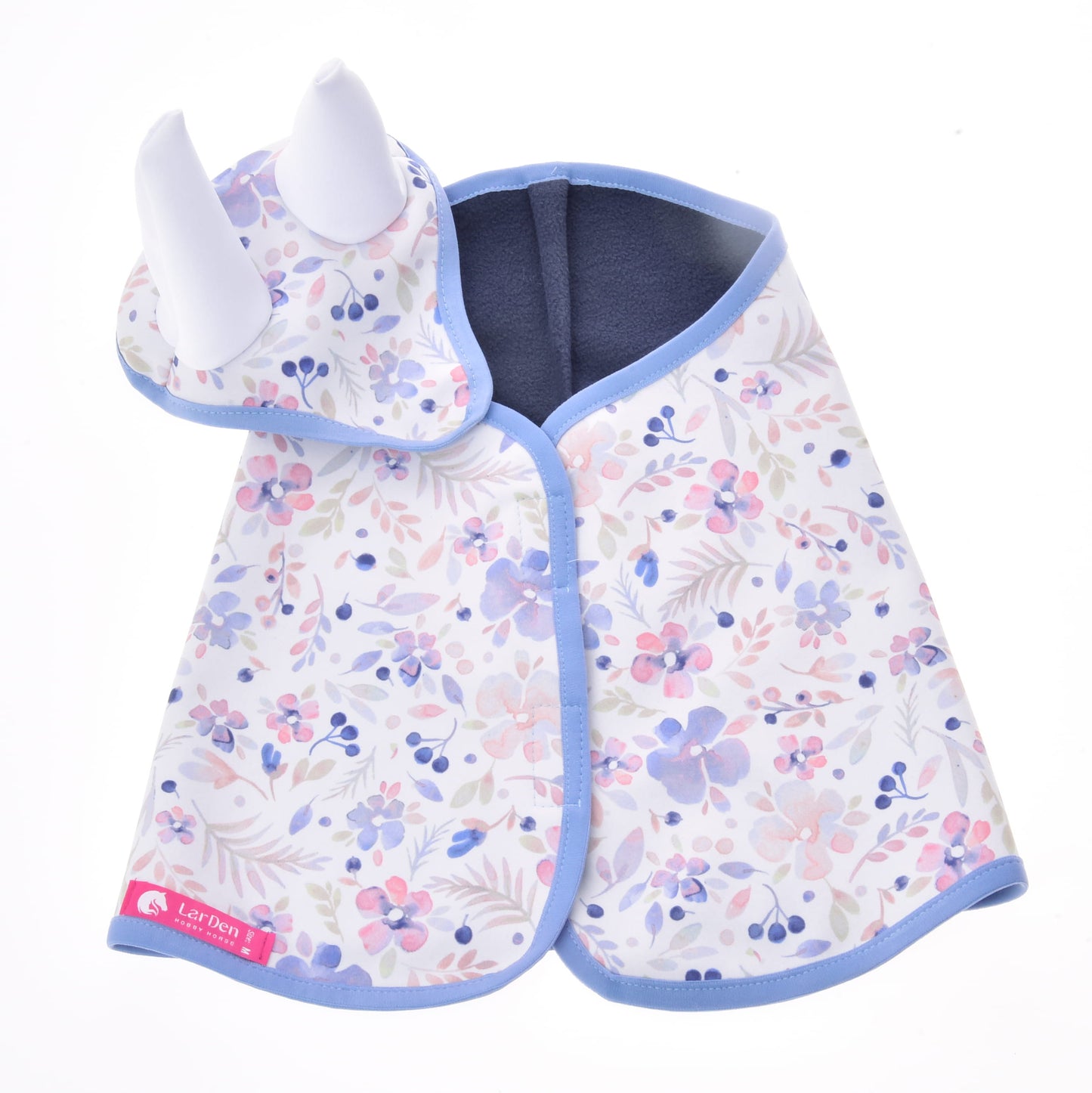 Set Vanessa NEW de Hobby Horse LarDen, avec cape pour bébé et bonnet assorti avec détails blancs en forme de corne et motif floral pastel avec bordure bleue, idéal comme ensemble couverture fantaisie ou bonnet d'oreilles ludique pour les tout-petits.