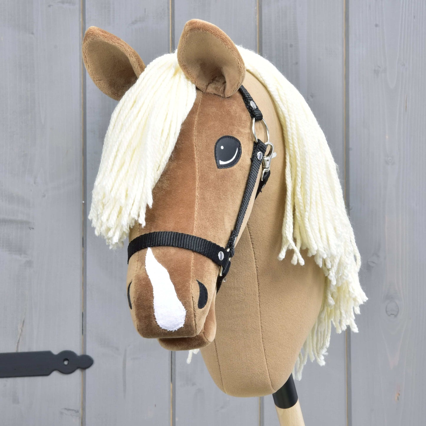 Hobby Horse Smart avec licol noir de Hobby Horse LarDen, avec visage brun clair, crinière blanche en fil, licol noir et liste blanche, parfait pour les disciplines western et le jeu imaginatif.