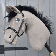 Hobby Horse Thor mit Schwarzem Halfter von Hobby Horse LarDen, ein Hobby Horse Hengst im Hannoveraner-Stil aus Plüsch, mit schwarzer Mähne, schwarzem Halfter und gestickten Augen, auf einem Holzstab vor einer hellgrauen Holzwand.
