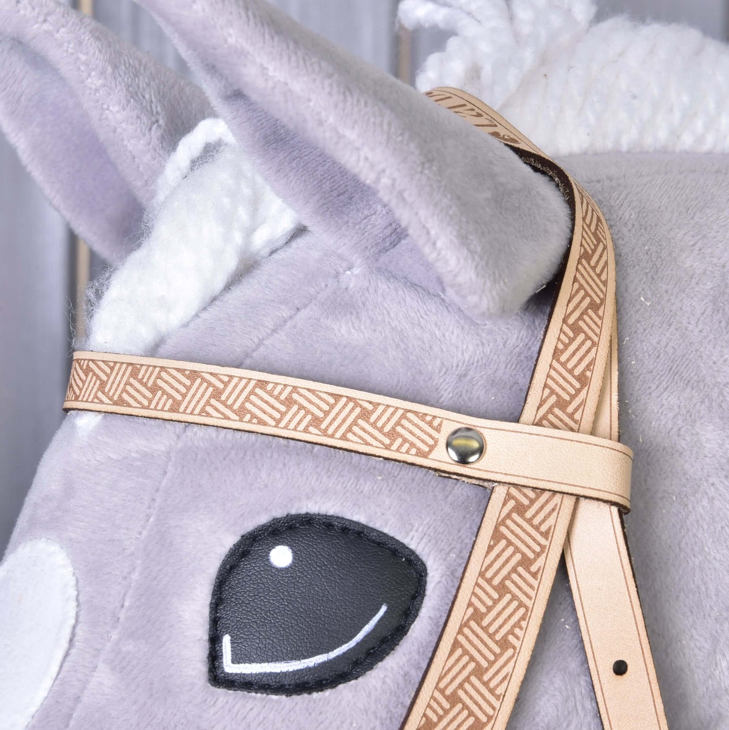 Gros plan sur la Bride Western Classique de Hobby Horse LarDen : tête de cheval en peluche gris clair avec yeux noirs cousus, détails blancs, bride western beige à motif, texture du tissu visible et crinière tressée.