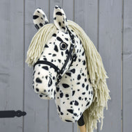 Hobby Horse Lord Valentine mit Schwarzem Halfter von Hobby Horse LarDen mit schwarz-weiß geflecktem Fell, Garnmähne und schwarzem Halfter vor grauem Holzhintergrund.