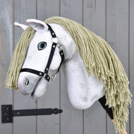 The Hobby Horse Victory with Black Halter - size M by Hobby Horse LarDen features a white plush head, blond yarn mane, black halter, and painted blue eye on a wooden stick, shown here before a gray wooden wall.
