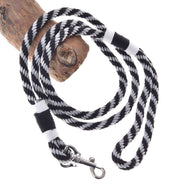 The Hobby Horse LarDen "Hobby Horse - Lead rope stripe black" is a black and white braided lead rope with a metal clip, ideal for hobby horses or real dogs, shown coiled around wood on a white background.